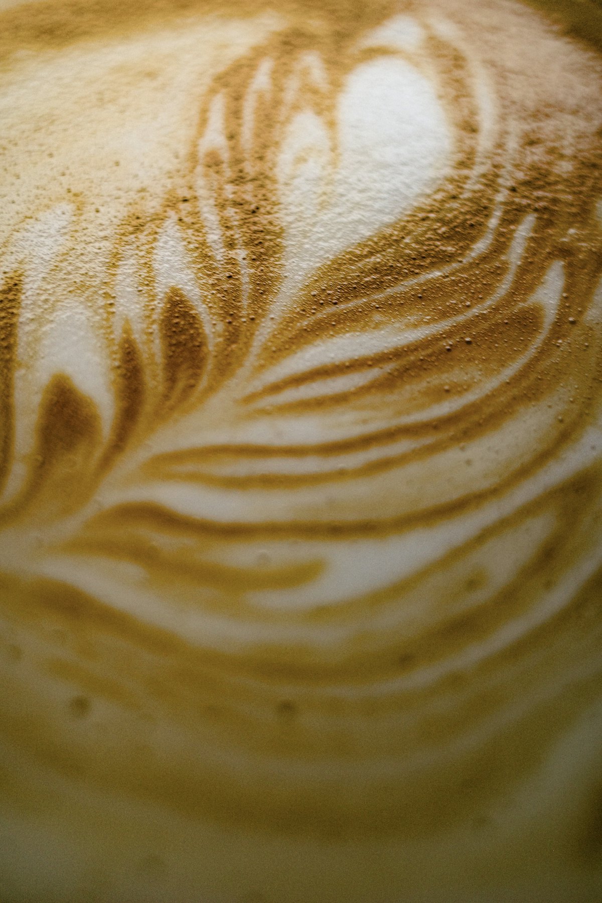 リーフ模様のラテアートが描かれた、なめらかなカフェラテ